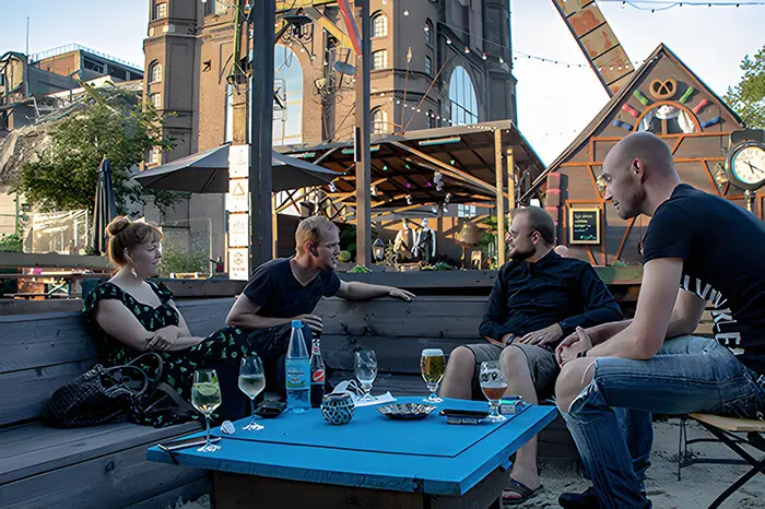Mehrere Menschen sitzen in einem Biergarten unter Sonnenschirmen.