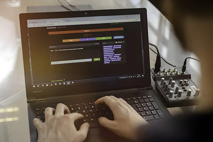 Hände tippen auf einem Laptop mit geöffneter Programmierumgebung.
